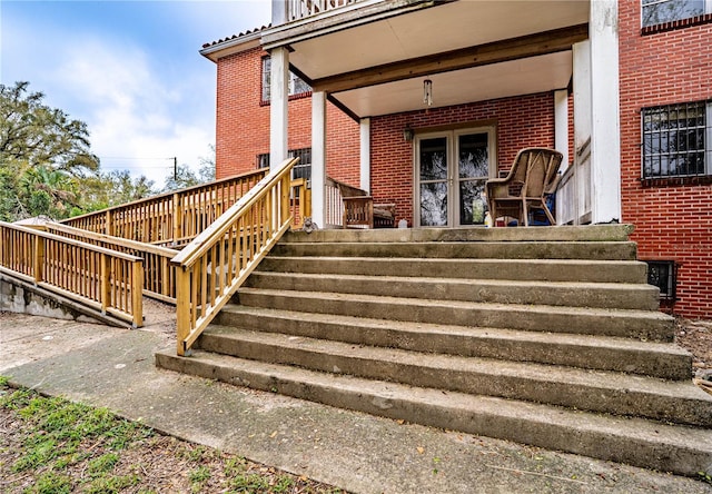 entrance to property with covered porch and brick siding