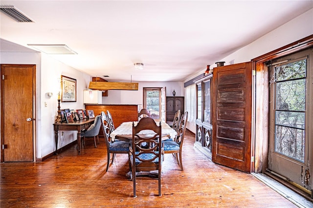dining room with wood-type flooring, visible vents, and baseboards
