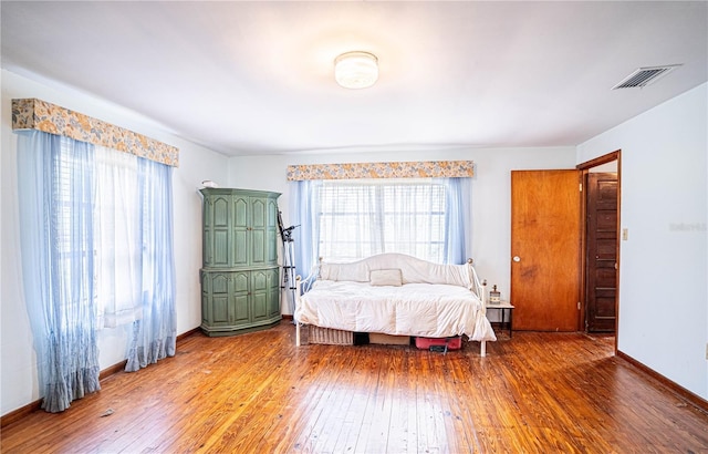 bedroom featuring hardwood / wood-style floors, visible vents, and baseboards