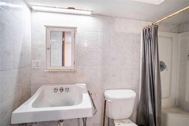 full bathroom with curtained shower, a sink, toilet, and tile walls
