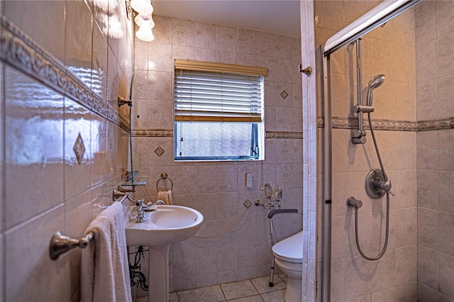 bathroom featuring toilet, tile patterned flooring, a shower stall, and tile walls