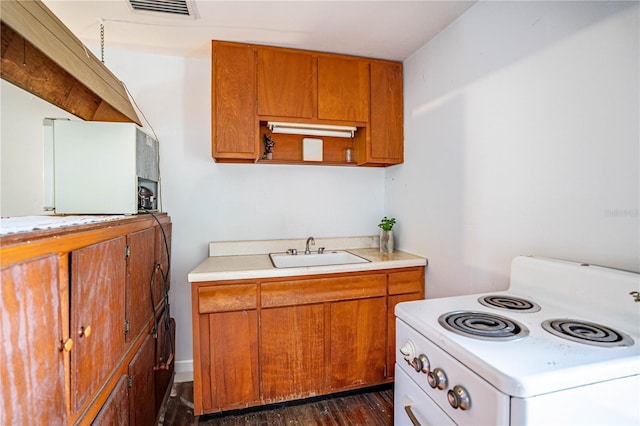 kitchen with light countertops, visible vents, electric range, brown cabinetry, and a sink