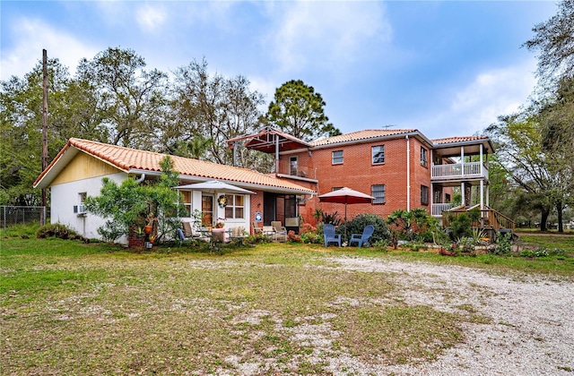 back of property with brick siding, a yard, and a tiled roof