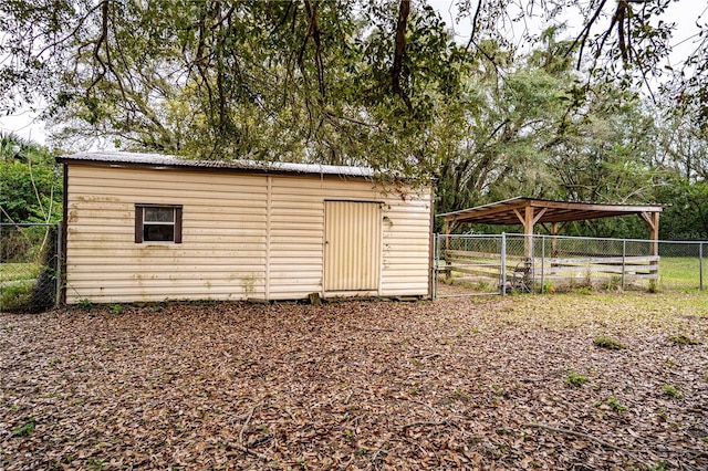 view of outdoor structure with an outbuilding, a carport, and fence