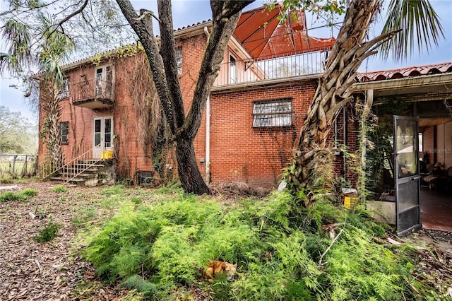 view of side of property featuring brick siding and a balcony