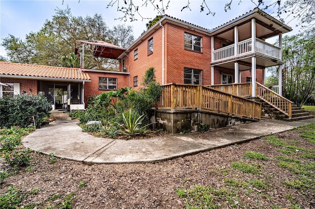 rear view of house featuring a balcony and brick siding