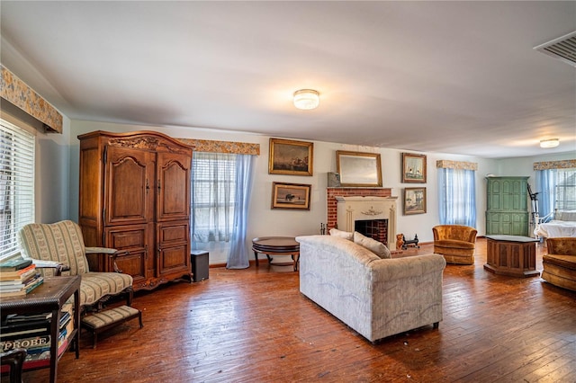 living room featuring a fireplace, dark wood finished floors, and visible vents