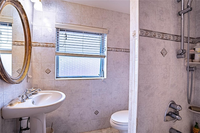 bathroom featuring toilet, a sink, walk in shower, and tile walls