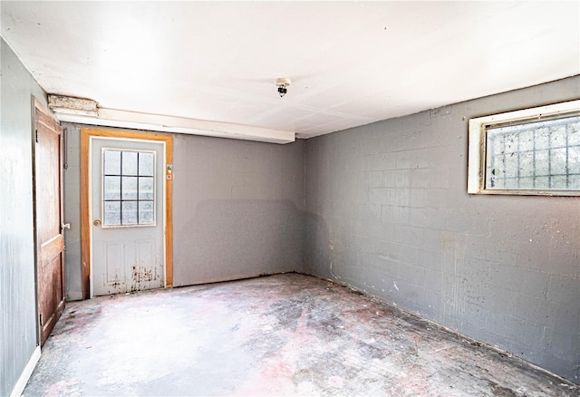 spare room with concrete block wall and unfinished concrete floors