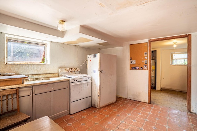 kitchen featuring white appliances, water heater, light countertops, and a sink