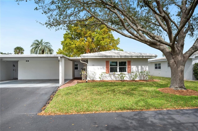 single story home with a carport, aphalt driveway, a front yard, and stucco siding