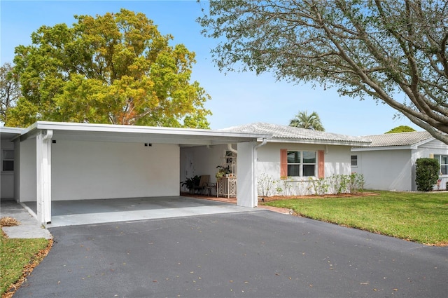 single story home with an attached carport, driveway, a front lawn, and stucco siding