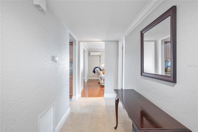 corridor featuring a textured wall, an AC wall unit, and visible vents