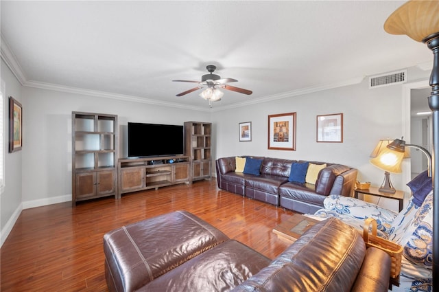 living area with wood finished floors, visible vents, baseboards, a ceiling fan, and ornamental molding