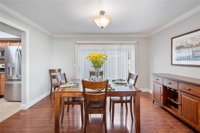 dining room featuring a textured ceiling, baseboards, and wood finished floors