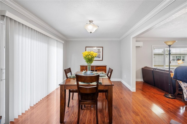 dining space with wood finished floors, crown molding, a textured ceiling, and a wall mounted AC