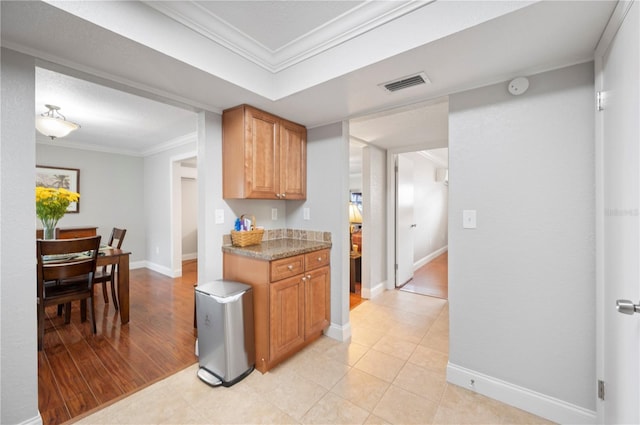 kitchen with visible vents, ornamental molding, baseboards, and light tile patterned flooring