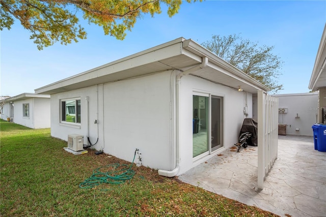 view of side of property featuring ac unit, a patio area, a yard, and stucco siding