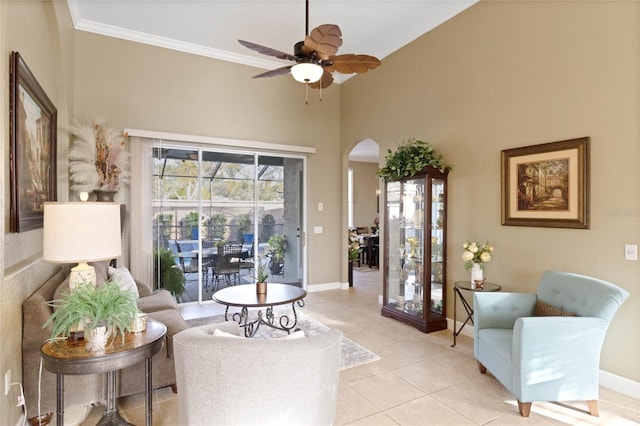 living area featuring ornamental molding, arched walkways, light tile patterned flooring, and baseboards