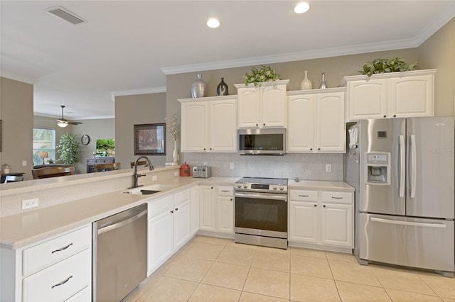 kitchen featuring light tile patterned floors, stainless steel appliances, a peninsula, a sink, and visible vents