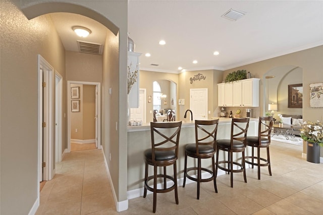 kitchen with arched walkways, light tile patterned floors, a breakfast bar area, and visible vents