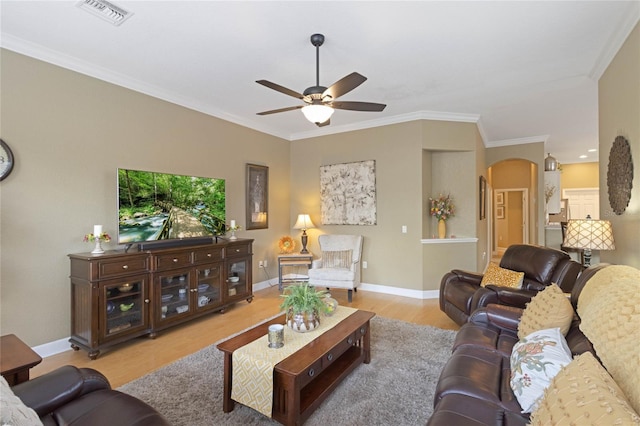 living room featuring arched walkways, crown molding, visible vents, wood finished floors, and baseboards