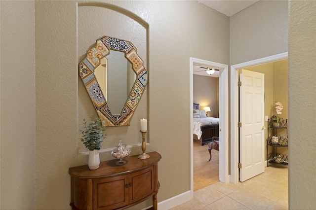 corridor featuring baseboards and light tile patterned floors