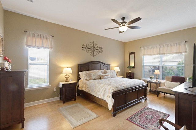 bedroom with light wood finished floors, ceiling fan, multiple windows, and baseboards