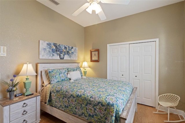 bedroom with ceiling fan, a closet, wood finished floors, and visible vents