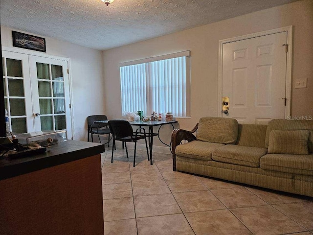 living room with french doors, a textured ceiling, and light tile patterned flooring