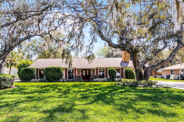 single story home featuring a chimney and a front lawn