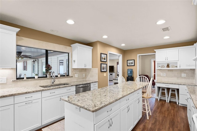 kitchen featuring dark wood-style floors, a sink, white cabinets, a center island, and dishwasher