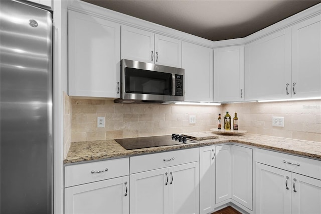 kitchen featuring appliances with stainless steel finishes, white cabinets, decorative backsplash, and light stone countertops