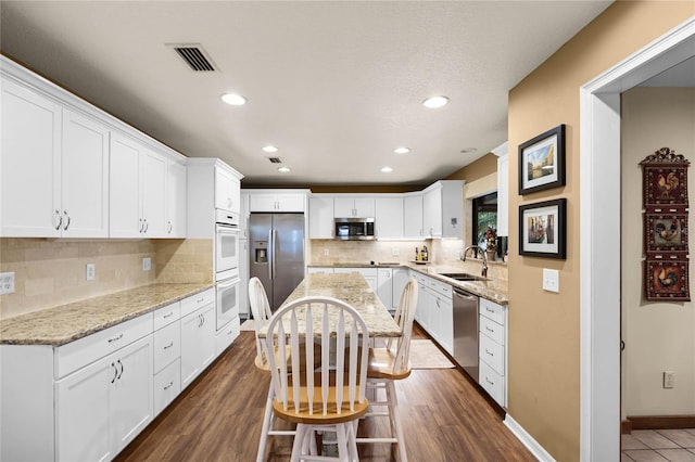 kitchen featuring visible vents, dark wood finished floors, appliances with stainless steel finishes, white cabinetry, and a sink