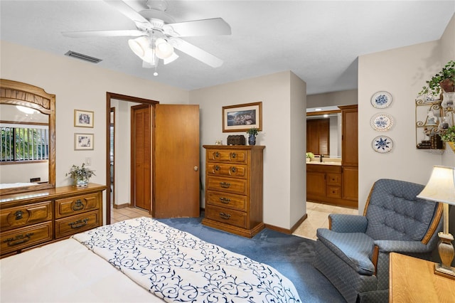 bedroom featuring visible vents, a ceiling fan, light carpet, ensuite bath, and baseboards