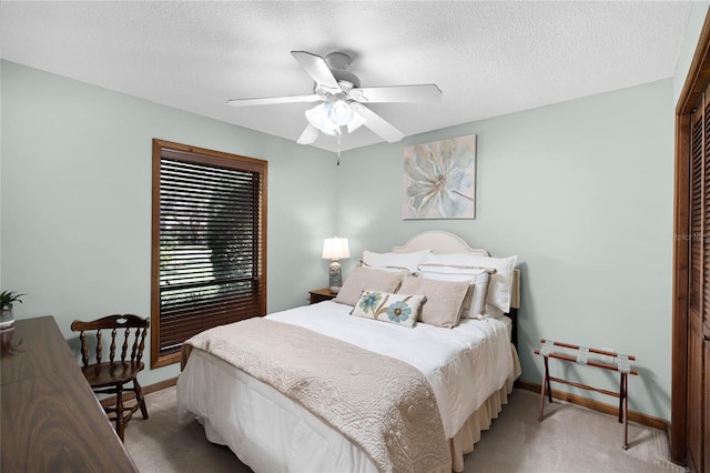 bedroom with a ceiling fan, baseboards, a textured ceiling, and light colored carpet