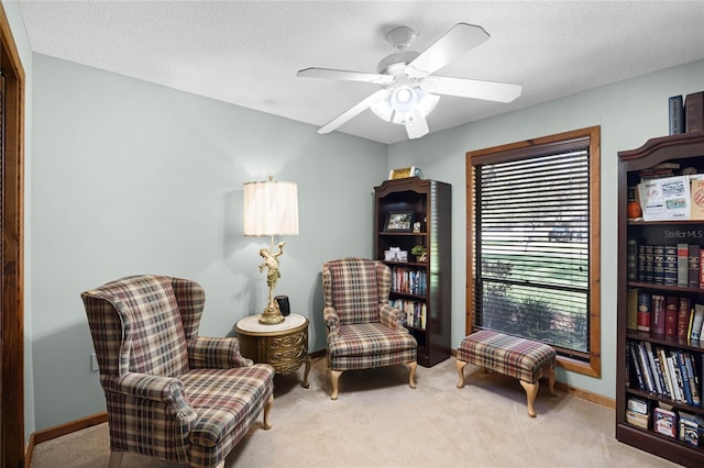 living area featuring a textured ceiling, carpet floors, ceiling fan, and baseboards