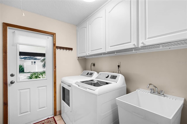 laundry room featuring a textured ceiling, independent washer and dryer, a sink, and cabinet space