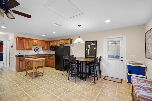 kitchen with brown cabinets, visible vents, light tile patterned flooring, a sink, and black appliances