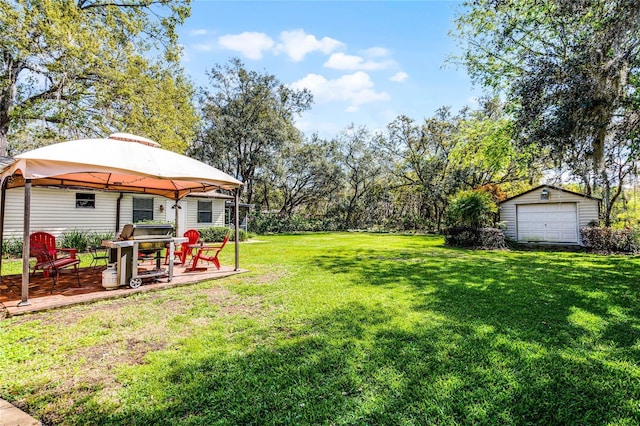 view of yard with a detached garage, an outdoor structure, and a gazebo