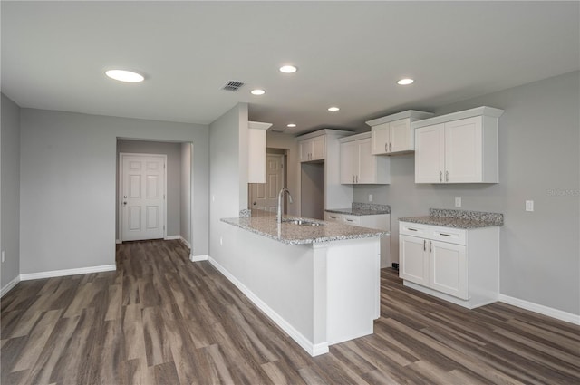 kitchen featuring visible vents, white cabinetry, a sink, light stone countertops, and a peninsula