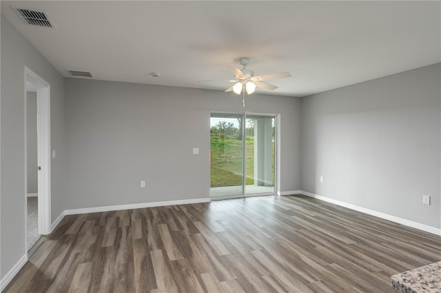 spare room featuring ceiling fan, wood finished floors, visible vents, and baseboards