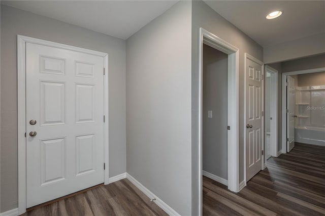 hallway featuring baseboards, dark wood finished floors, and recessed lighting