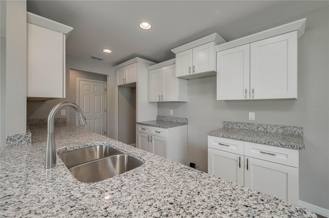 kitchen with recessed lighting, a sink, visible vents, white cabinetry, and light stone countertops