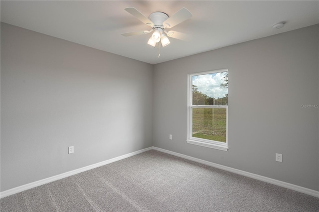 carpeted empty room featuring ceiling fan and baseboards