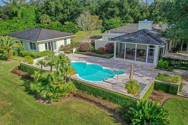 pool featuring a sunroom, a lawn, and a patio