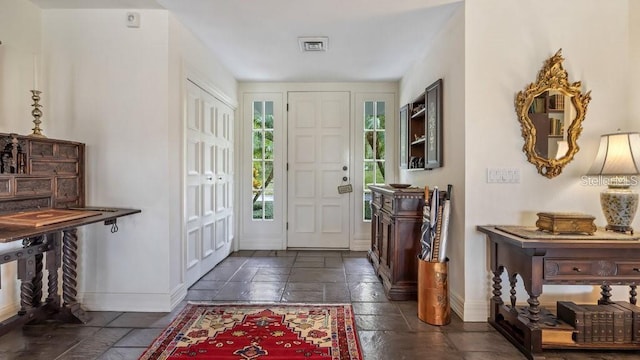 entrance foyer with baseboards and stone tile floors