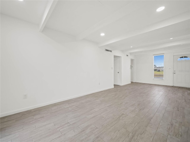 spare room featuring baseboards, visible vents, beamed ceiling, and wood finished floors