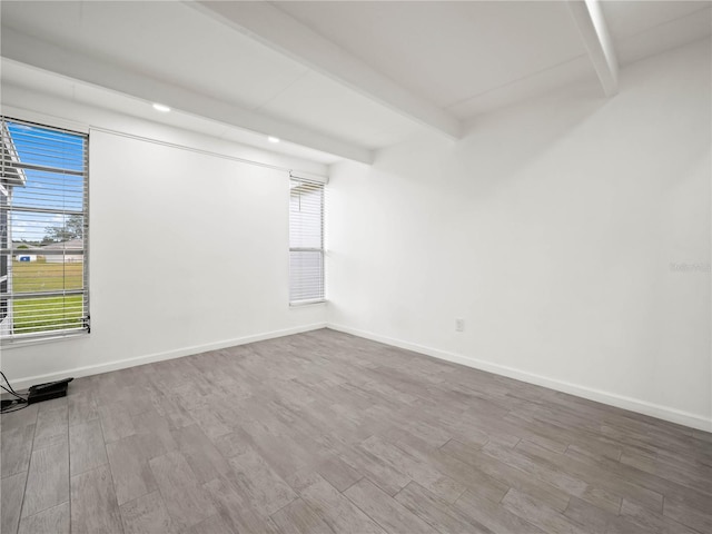 spare room with beamed ceiling, wood finished floors, and baseboards