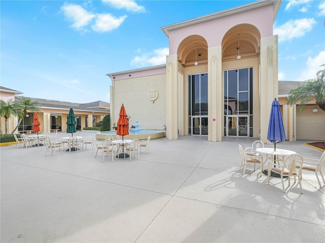 back of house with outdoor dining area, a patio area, and stucco siding